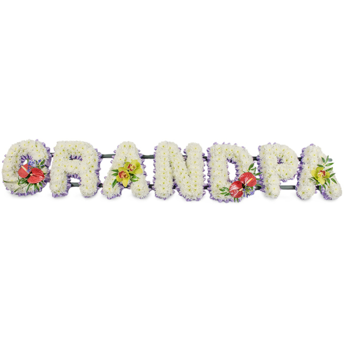 In this dignified funeral arrangement, the word GRANDPA stretches horizontally in bold, block capital letters, each character completely covered in pristine white chrysanthemums. The flowers are closely packed to form a smooth, plush surface, resembling soft cushions laid side by side. Every letter is framed along the base with a narrow band of light purple or lavender ribbon, giving a gentle outline that subtly lifts the white blooms from the clean white background. Behind the scenes, dark green support bars link the letters, providing stability so the tribute can rest neatly on a stand at a Colney Hatch funeral service, perhaps in a quiet chapel or at the graveside in a local cemetery.   

The design is brought to life by four carefully planned sprays of accent flowers that add colour and meaning. On the far left, the 'G' is decorated with a striking cluster of deep red anthuriums, their glossy, heart-shaped petals and central yellow spadices catching the eye, surrounded by rich foliage and perhaps a few delicate filler blooms. Towards the centre-right, the 'D' mirrors this effect with another group of red anthuriums and greenery, creating a strong line of remembrance through the tribute. Balancing these rich reds, the first 'A' and the last 'A' feature sprays of yellow-green orchids, their graceful, arching heads and intricate petals conveying refinement and enduring affection. The orchids sit amongst lush green leaves, offering a softer, more delicate note alongside the bold anthuriums.   

The overall mood is peaceful and respectful, perfectly suited to honouring a much-loved grandad from the Colney Hatch community. It is the kind of personalised name tribute local families might choose when they want funeral flowers that carry both a clear message and a gentle, heartfelt presence.