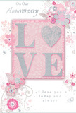 This anniversary card feels like a whispered declaration of enduring romance, designed with the same gentle attention to detail you might find in a hand-crafted arrangement delivered across Colney Hatch. The centre of the card is devoted to the word LOVE, each letter raised and coated in a soft, glistening glitter that offers both visual sparkle and a pleasing texture under the fingertips. The O is transformed into a shimmering silver heart, its surface slightly more pronounced, adding a focal point that suggests a treasured bond. Surrounding this central motif, delicate blooms in blush pink and muted mauve unfold with a watercolour softness, their petals outlined in fine, flowing lines and accented with subtle hints of silver and pale grey. Wisps of vines, tiny petals, and light, swirling flourishes weave between the flowers, lending the composition a sense of motion, like a gentle breeze moving through a spring garden tucked behind homes near Colney Hatch Park. Small butterflies and faint decorative curls appear almost as secret details, rewarding a lingering gaze. The script On Our Anniversary and the heartfelt phrase I love you today and always are written in graceful, understated lettering that curves naturally with the floral forms, enhancing the feeling of sincerity. Set against a tender pink backdrop, the entire card glows softly, evoking intimacy, shared memories, and the quiet joy of celebrating another year together in Colney Hatch.